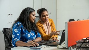Two women talking in front of a computer