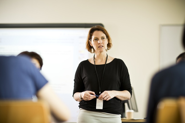 a teacher walking in a classroom, preparing students to meet language requirements for work in Canada